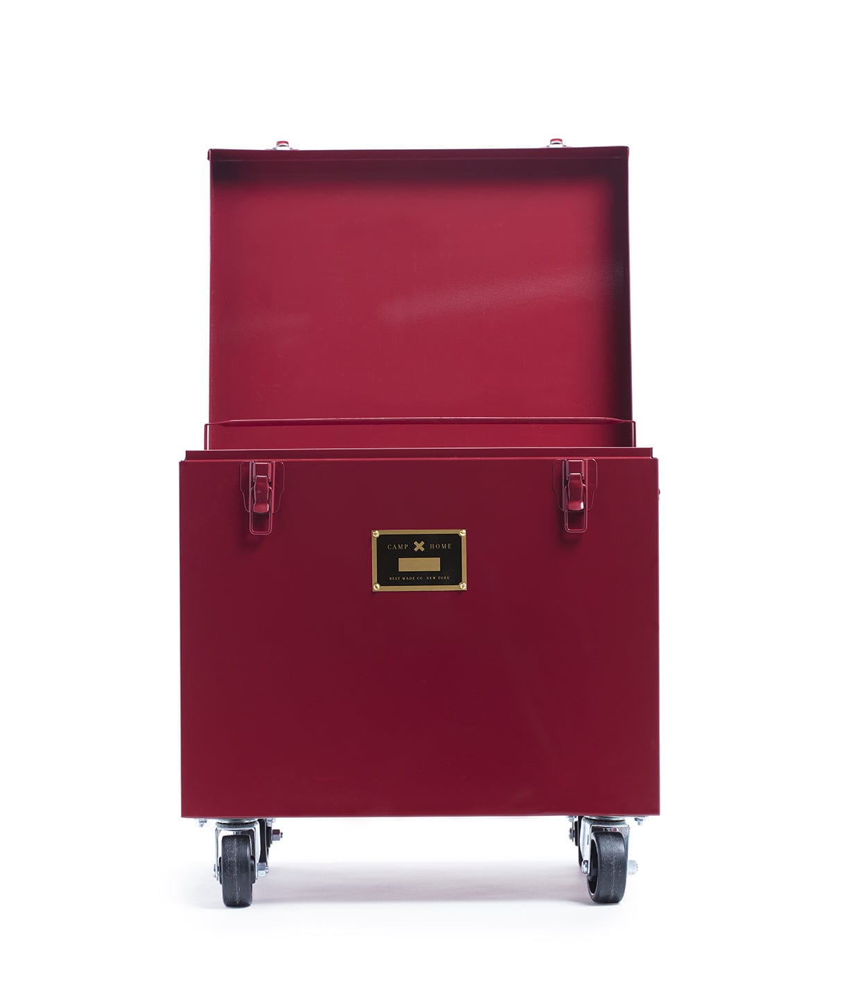 A Rolling Footlocker by Best Made Company Archive, crafted from heavy-duty 22-gauge steel in red, features a hinged lid open and four caster wheels for mobility. A black and gold nameplate adorns the front of the metal trunk, which is photographed against a plain white background.